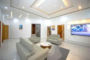 uma sala de estar com um sofá e duas cadeiras e uma televisão em RESIDENCE TERANGA immo luxe em Dakar