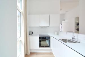 a white kitchen with white cabinets and a sink at Great Apt · Near Beach · CPH in Copenhagen