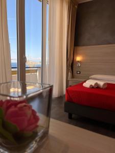 una camera d'albergo con letto e ciotola di vetro con un fiore di B&B Margherita a Messina