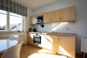 a kitchen with wooden cabinets and a table and a window at Dünenblick Wohnung 17 in Boltenhagen