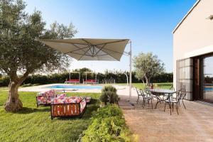 patio con tavolo, sedie e ombrellone di Villa Balate - Countryside Luxury Experience a Ragusa