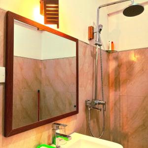 a bathroom with a shower and a sink and a mirror at Jagabay Resort & Surfing School in Weligama