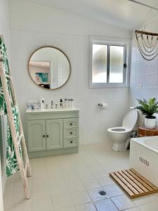 a bathroom with a sink and a toilet and a mirror at Long Jetty Lake House in Long Jetty