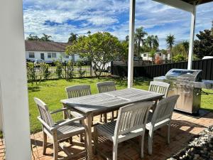 a wooden table and chairs on a patio with a grill at Long Jetty Lake House in Long Jetty