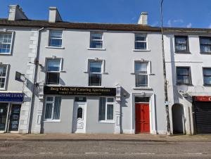 a white building with a red door on a street at Derg Valley Apartments in Castlederg