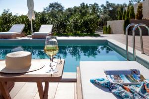a glass of wine sitting on a table next to a pool at Zavia Resort in Syvota