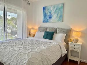 a white bedroom with a large bed and a window at Long Jetty Lake House in Long Jetty