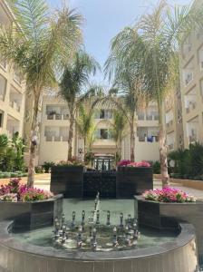 a fountain in the middle of a courtyard with palm trees at Excellent appartement S+2 au PALM lake resort in Monastir