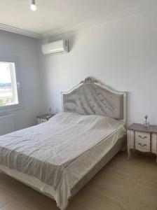 a white bed in a white bedroom with two tables at Excellent appartement S+2 au PALM lake resort in Monastir
