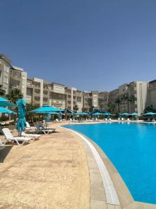 a large swimming pool with chairs and umbrellas at Excellent appartement S+2 au PALM lake resort in Monastir