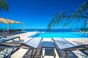 a swimming pool with chairs and the ocean in the background at Nafsika Xenia - Ariti Villa in Plátanos