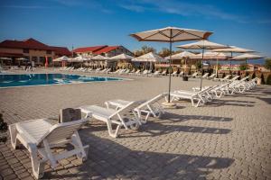 una fila de sillas y sombrillas blancas junto a una piscina en ILLARA SPA Hotel en Irshava
