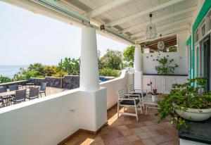 d'un balcon avec des chaises et des tables donnant sur l'océan. dans l'établissement Villa Mareblu Luxury Holiday Apartment direttamente sul mare, à Stromboli