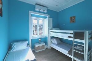 um quarto azul com 2 beliches e uma janela em International Surf School & Camp em Sagres