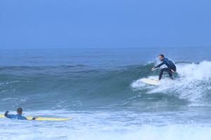 two men riding a wave on surfboards in the ocean at International Surf School & Camp in Sagres