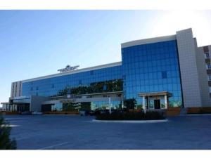 a large glass building with a parking lot in front at Grand Nur Plaza Hotel in Aktau