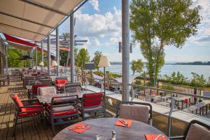 een restaurant met tafels en stoelen en uitzicht op het water bij Lodge Hôtel & Spa Les Voiles du Grand Large in Meyzieu