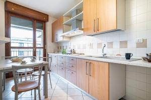 a kitchen with wooden cabinets and a table and chairs at Broletto Park Apartment - Affitti Brevi Italia in Lecco