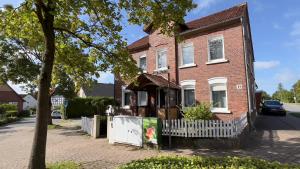 ein rotes Backsteinhaus mit einem weißen Zaun in der Unterkunft Pension Reiter in Blomberg