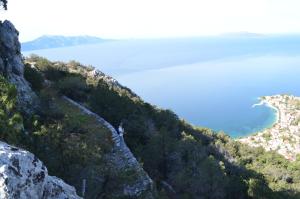 a person standing on the side of a mountain overlooking a body of water at Apartments Palma in Gradac