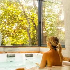 una mujer sentada en una bañera mirando por la ventana en Quinta do Pedregal Hotel & Spa, en Lever