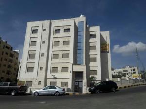 a building with two cars parked in front of it at Dair Ghbar 2-bedrooms unit in Amman