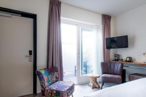 a hotel room with a bed and a chair and a window at Boutique Hotel De Eilanden in Harlingen