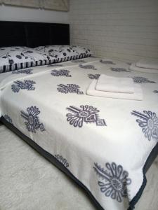 Una cama con una manta blanca con flores azules. en Apartament u Busiów - okolice Zakopanego, en Dzianisz