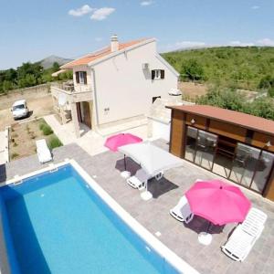 ein Pool mit Sonnenschirmen und Stühlen und ein Haus in der Unterkunft Villa RoseMary near Split in Donje Ogorje