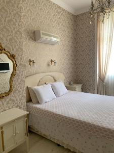 a bedroom with a bed with white sheets and a mirror at Tsar Simeon Veliki in Stara Zagora