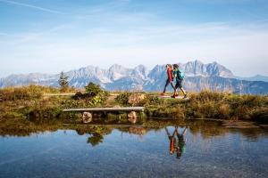 dos personas caminando a través de un puente sobre un cuerpo de agua en Garten Suite Kirchberg by Alpine Host Helpers en Kirchberg in Tirol