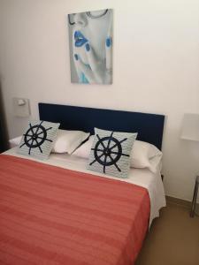 a bed with two pillows and a painting on the wall at b&b Le Rocce in San Vito lo Capo