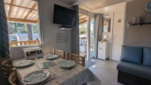 a living room with a dining table and a television at Mobilhome Eleganzia 713 Bonne Anse Plage in Les Mathes