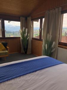 a bedroom with a bed and windows with flowers at PanoramaApart - Alpzeit im Westallgäu in Oberreute