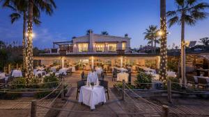 ein Restaurant mit weißen Tischen, Stühlen und Palmen in der Unterkunft Villa close to the beach in Marbella in Marbella