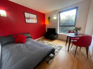 a red bedroom with a bed and a table at Iconic City Centre Apartment in the Devonshire Quarter in Sheffield