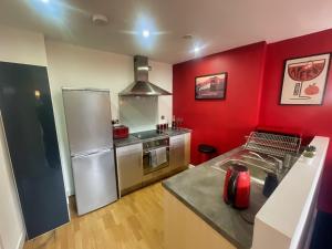 a kitchen with red walls and stainless steel appliances at Iconic City Centre Apartment in the Devonshire Quarter in Sheffield