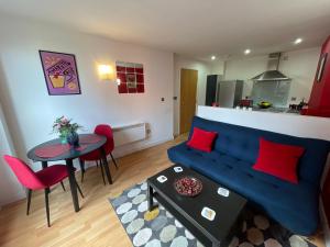 a living room with a blue couch and a table at Iconic City Centre Apartment in the Devonshire Quarter in Sheffield