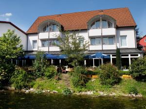 a building with tables and chairs next to a river at Hotel und Gästehaus Kreuz in Gammertingen