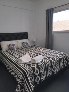 a bedroom with a black and white bed with a window at Dpto CERCANIA in San Fernando