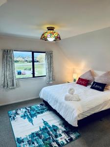 a bedroom with a bed with a window and a rug at River Cottage in Blenheim