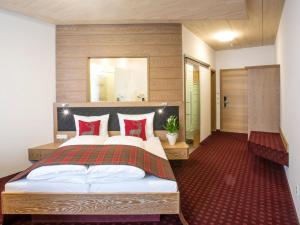 a bedroom with a large bed with red pillows at Hotel und Gästehaus Kreuz in Gammertingen