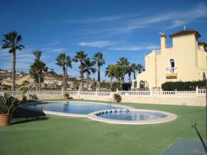 a swimming pool in front of a house with palm trees at Casa Yvonne in Rojales