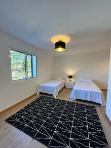 a bedroom with two beds and a black and white rug at The Passion Fruit House in São Vicente