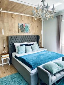 Schlafzimmer mit einem großen Bett mit blauer Bettwäsche und einem Kronleuchter in der Unterkunft IrányBerény Rezidencia in Balatonberény