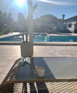 een kopje koffie zittend op een tafel naast een zwembad bij Villa Torrealta, 4000 m2, estancia mínima en verano 7 días de sábado a sábado in Cádiz
