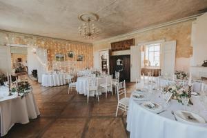 uma sala cheia de mesas e cadeiras com toalha de mesa branca em Blankenfeldes muiža em Tervete