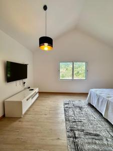 a white room with a bed and a flat screen tv at The Passion Fruit House in São Vicente