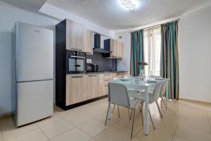 a kitchen with a table with chairs and a refrigerator at Sliema Tigne Suites in Sliema