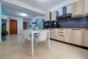 a kitchen with a white table and white chairs at Sliema Tigne Suites in Sliema